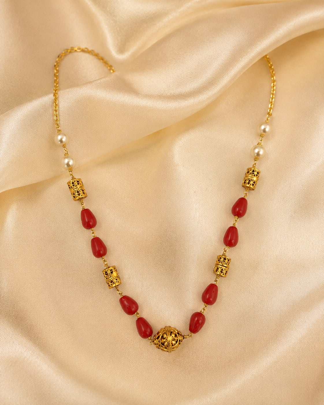 Coral Red Oval Bead Necklace – coral red beaded necklace styled on rich fabric – view 3