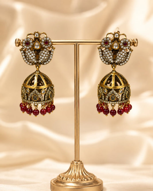 Peacock Victorian-Style CZ Jhumka Earrings with Red Bead Fringe – ruby jhumka earrings on jewellery display – front view