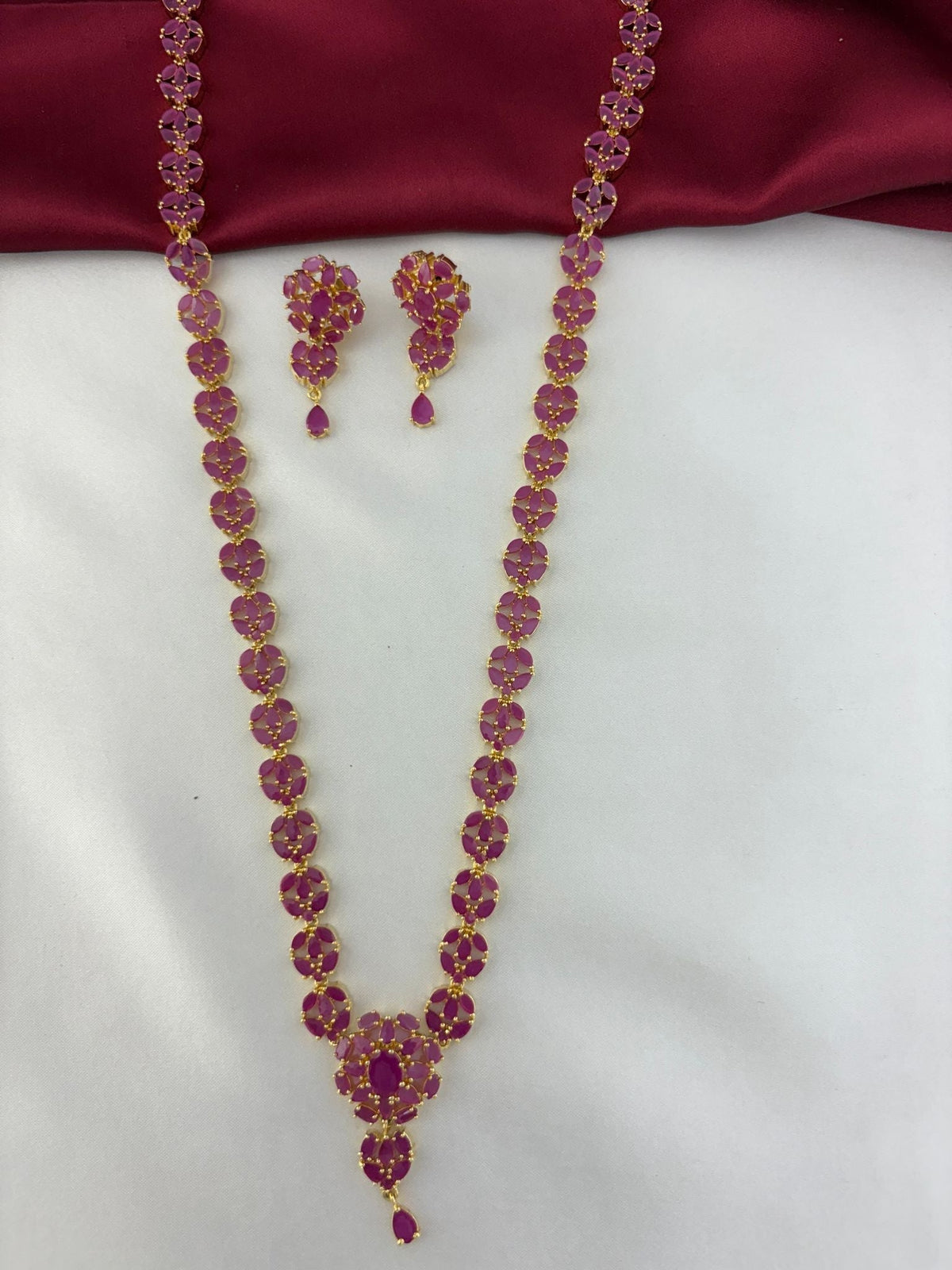 Overhead shot of the Vintage Vine Ruby Long Necklace & Earring Set against a contrasting background – view 3